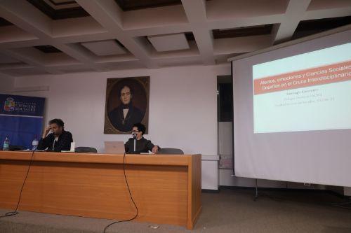 “Afectos y Ciencias Sociales. Desafíos para la investigación interdisciplinaria”, se tituló la conferencia magistral de Santiago Canevaro, investigador de la Escuela Interdisciplinaria de Altos Estudios Sociales (IDAES) de la Universidad Nacional de San Martín, Argentina, realizada el 03 de junio en el marco de las actividades del Colegio Doctoral de la Facultad de Ciencias Sociales. Canevaro abordó algunos de los principales desafíos epistemológicos y metodológicos presentes en el estudio de las emociones y afectos como parte importante de la vida social. Al respecto, planteó la necesidad de entender las emociones como procesos relacionales y no únicamente individuales, en la medida que representan construcciones históricas atravesadas por regulaciones institucionales y normas sociales. Esto desafía a investigar las emociones y afectos no solo a partir de lo que dicen las personas, sino a través de lo que hacen, sus prácticas y contextos. A su vez, Canevaro sugirió la importancia de abordar las emociones y afectos en sus contextos históricos y culturales. Según el investigador argentino, a diferencia de otras sociedades, en América Latina una hibridez entre instituciones formales y afectos representaría una constante histórica, expresando una forma de individualismo sui generis.  También se refirió a los problemas y aproximaciones relativas al hablar de las emociones, por un lado, y los afectos por otro. Las emociones tienen un énfasis en códigos culturales, variaciones culturales de lo que se nombra, tienden a desnaturalizar las palabras e invitan a captar el régimen emocional en su contexto. Los sujetos pueden narrarlas, por lo que poseen una tradición psicológica, antropológica y sociológica. Los afectos, por su parte, tienen la particularidad de que no se expresan con palabras y son efímeros, circulan entre cuerpos y objetos, hay en ellos una necesidad de metodologías que capturen otros sentidos (corporal, sensorial, observación densa), poniendo atención en el tono y ritmo, utilizando dispositivos visuales, performativos o materiales.  Canevaro relevó la mirada interdisciplinaria como una oportunidad y desafío al mismo tiempo, destacando al respecto que dentro de sus ventajas permite el enriquecimiento de la comprensión a partir de diferentes registros (psique, cuerpo, cultura, lenguaje). Estos registros enlazan lo individual y lo colectivo, combinando herramientas metodológicas tales como la etnografía, entrevistas y análisis de discurso, entre otras. Sin embargo, la interdisciplina también conlleva ciertos riesgos que se deben atender, tales como una posible pérdida de rigor disciplinar, hibridación superficial y malentendidos conceptuales.  La actividad contó con la activa participación de estudiantes de distintos programas de doctorado de la facultad, quienes plantearon reflexiones e interrogantes a propósito de sus proyectos de investigación.  El subdirector de la Escuela de Postgrado, Camilo Sembler, acentuó el desarrollo de la conferencia como parte de las actividades que se realizan en el Colegio Doctoral, buscando promover la colaboración y el trabajo interdisciplinario entre los distintos programas de doctorado de la Facultad de Ciencias Sociales
